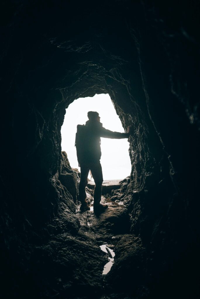 A person standing in a cave with the sun shining
